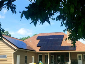 A single-family home with a brown shingle roof has newly installed solar panels.