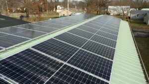 A large array of solar panels installed on the metal roof of a commercial building.