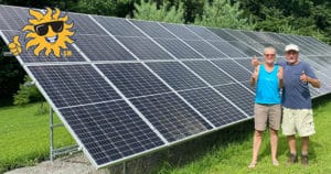 A couple stands in front of groun-mounted solar panels that were just installed on their property.