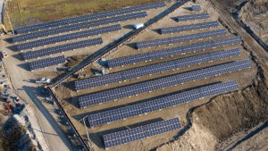 An aerial multiple rows of large solar panels array mounted on the ground for commercial use.