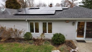 A single-story home with vinyl siding has new solar panels installed on the roof.