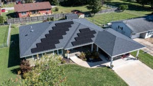 A drone image of a large home with solar panels installed on one side of the roof.