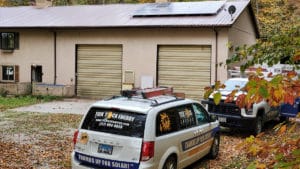 A small home with a two-car garage has solar panels on the roof.