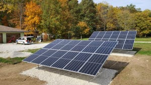 Two rows of ground-mounted solar panels at a residential home.