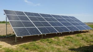 A large solar array mounted on the ground on a commercial property.